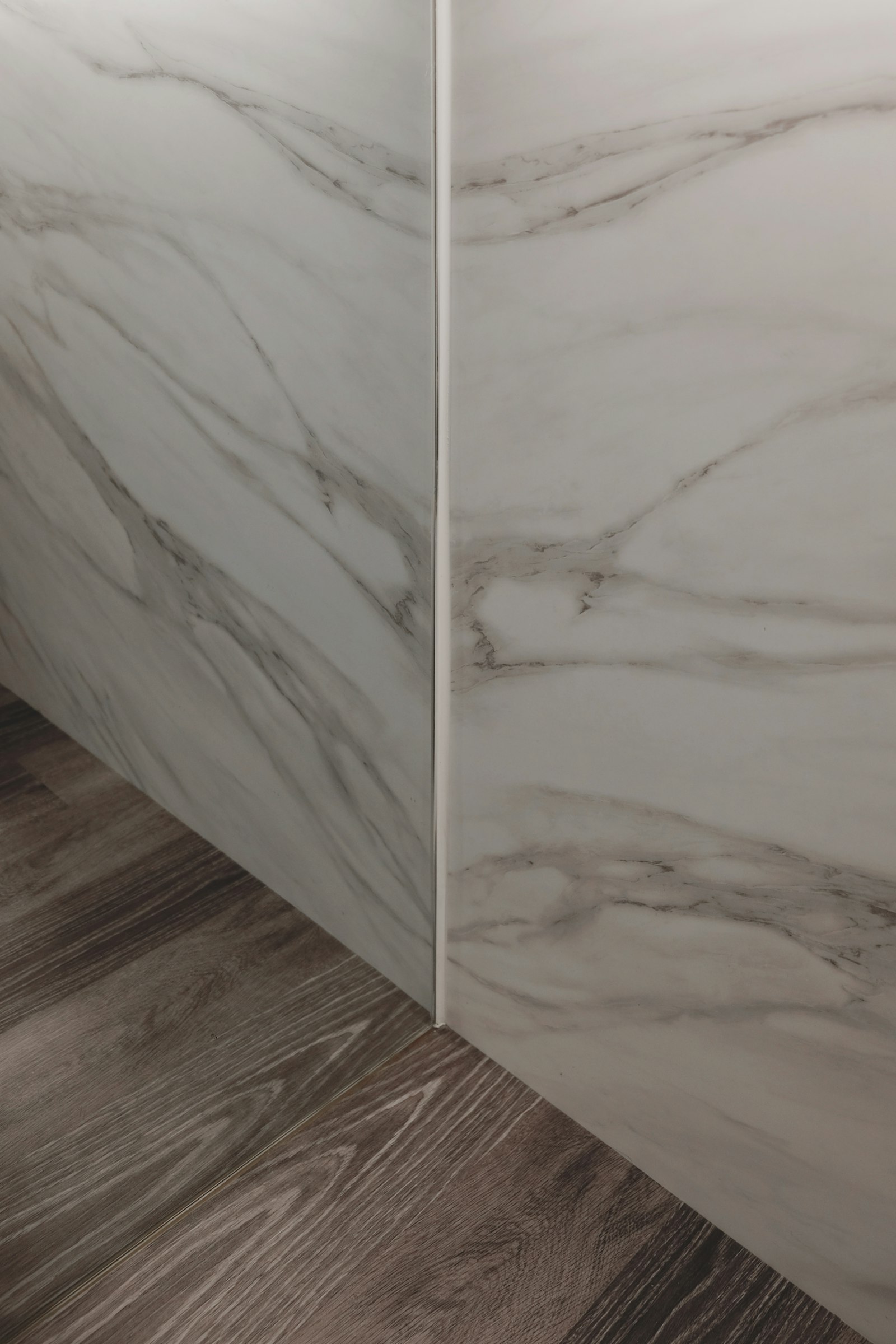 Detail of marble wall meeting parquet wood floor